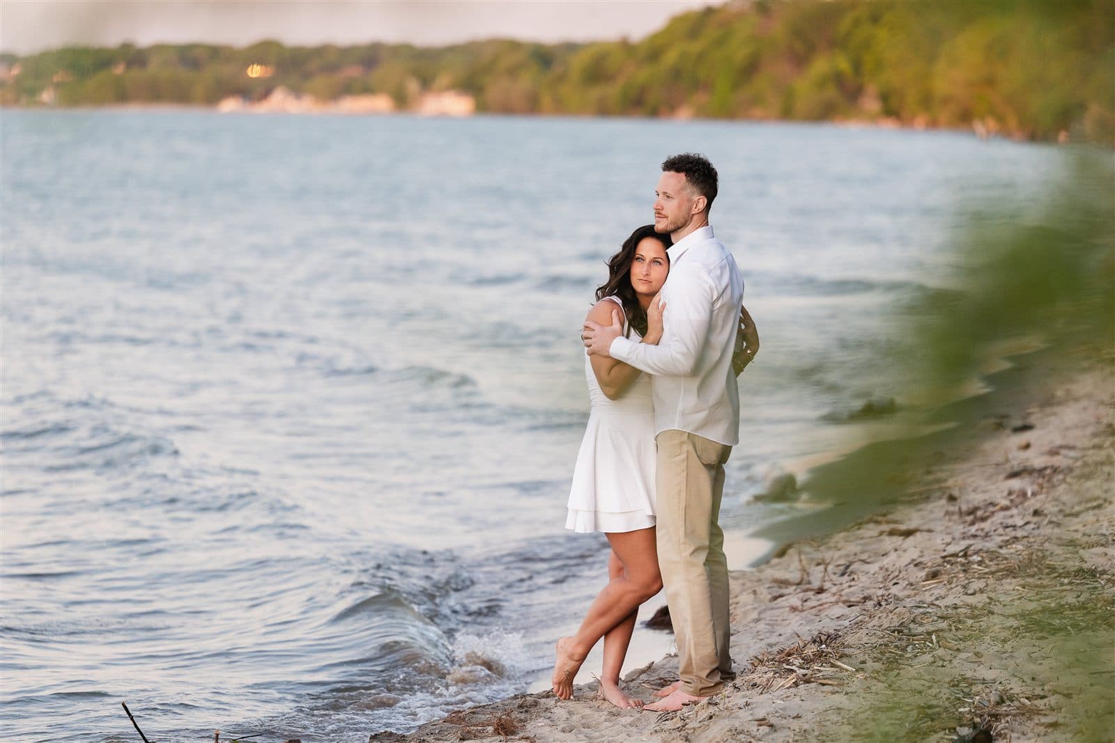 Danielle and Sheldon standing together at the edge of Lake Ontario at golden hour