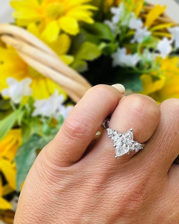 Danielle's engagement ring on her hand, with yellow flowers behind